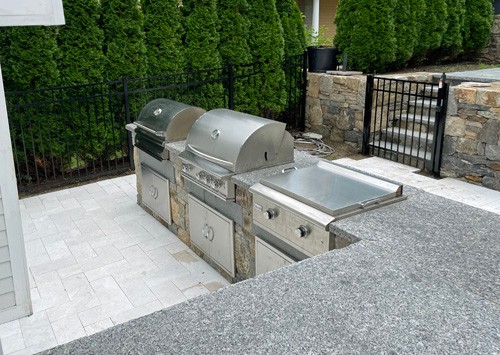 Stone bar with wood grill, griddle and gas grill by New View