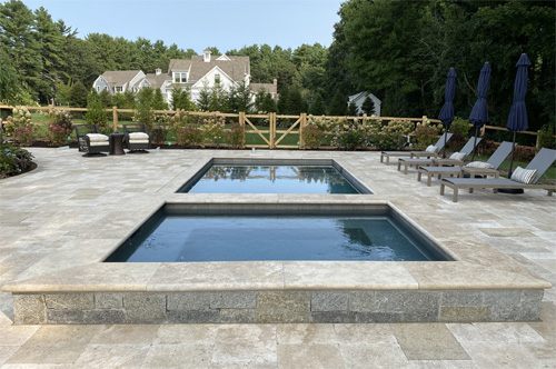 Spa and Pool with travertine patio and stone walls by New View